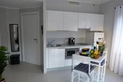 a kitchen with white cabinets and a table with fruit on it at Grand & beau studio climatisé vue sur mer in Propriano