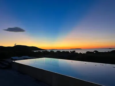 a swimming pool with a sunset in the background at Porto-Vecchio Palombaggia Villa Azaïtù in Porto-Vecchio