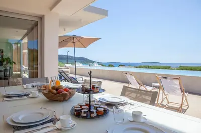 a table with plates of food on a balcony at Porto-Vecchio Palombaggia Villa Azaïtù in Porto-Vecchio