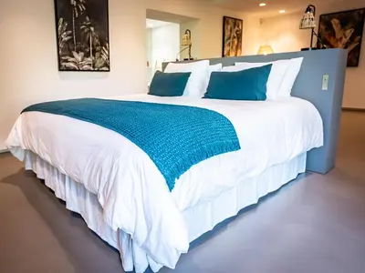 a large white bed with blue and white pillows at Porto-Vecchio Palombaggia Villa Azaïtù in Porto-Vecchio