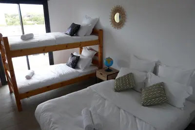 a white bed with two slippers on top of it at T3 Le Myrte vue Mer & Montagne idéalement situé in Propriano