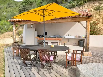 a table and chairs with an umbrella on a deck at A Vignarella in Ventiseri