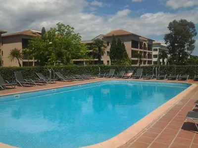 a large swimming pool with chairs and a building at MORIANI STUDIO CABINE CLIMATISE 4 à 5 pers in San-Nicolao