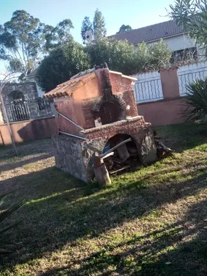 a brick oven sitting in the grass in a yard at Un Nid Douillet en bord de plage !! in Lucciana