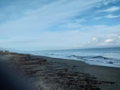 a beach with the ocean on a cloudy day at Un Nid Douillet en bord de plage !! in Lucciana