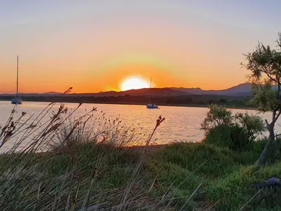 a sunset over a body of water with boats at L'ortu di Quaprice in Figari