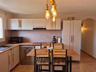 a kitchen with a table and chairs and a refrigerator at L'ortu di Quaprice in Figari