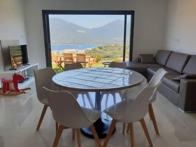 a living room with a table and chairs and a couch at Appartement neuf 3 chambres vue mer Propriano in Propriano