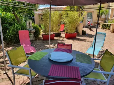 a table with colorful chairs and an umbrella at Villa les palmiers -Stretta di i mandarini in Lucciana