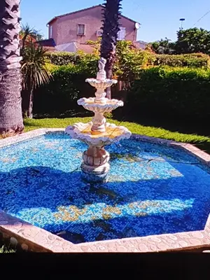 a fountain in front of a pool with blue water at Villa les palmiers -Stretta di i mandarini in Lucciana