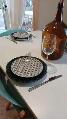 a table with two plates and wine glasses on it at Le petit chalet de Charlène in San-Gavino-di-Carbini