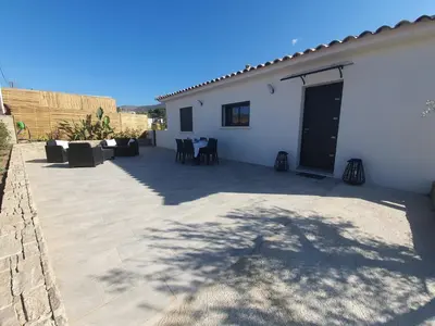 a patio with a white house with a black door at Villa l'alivu in Afa