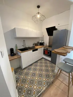 a kitchen with white cabinets and a floor with a table at F2 Glamour Centre ville historique in Ajaccio