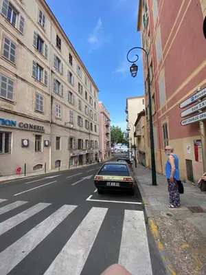 a woman standing on the side of a street with a car at F2 Glamour Centre ville historique in Ajaccio