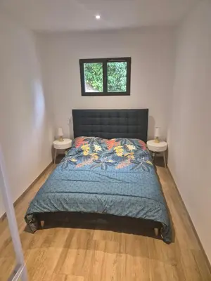a bedroom with a bed with two night stands at Rez de villa avec piscine privée, wifi, jardin clôturé in Penta-di-Casinca