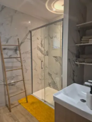 a bathroom with a shower with a glass door at Rez de villa avec piscine privée, wifi, jardin clôturé in Penta-di-Casinca
