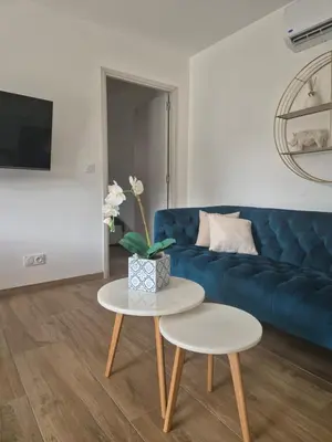 a living room with a blue couch and a table at Rez de villa avec piscine privée, wifi, jardin clôturé in Penta-di-Casinca