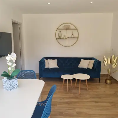 a living room with a blue couch and two tables at Rez de villa avec piscine privée, wifi, jardin clôturé in Penta-di-Casinca