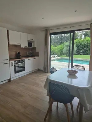 a kitchen and dining room with a table and chairs at Rez de villa avec piscine privée, wifi, jardin clôturé in Penta-di-Casinca