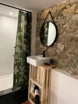 a bathroom with a sink and a mirror on a stone wall at Chez LULU appartement de caractère in Cozzano