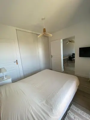 a bedroom with a white bed and a dining room at Ajaccio magnifique T2 40m2 centre ville vue mer au bord de la plage neuf 5 personnes Clim wifi balcon parking privé fermé in Ajaccio