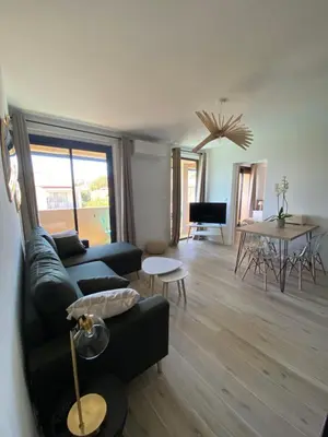 a living room with a black couch and a table at Ajaccio magnifique T2 40m2 centre ville vue mer au bord de la plage neuf 5 personnes Clim wifi balcon parking privé fermé in Ajaccio