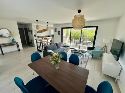 a living room with a wooden table and blue chairs at Cala Rossa, Pinarello, Saint Cyprien - La Villa D'Alice in Lecci