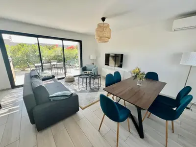 a living room with a couch and a table and chairs at Cala Rossa, Pinarello, Saint Cyprien - La Villa D'Alice in Lecci