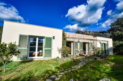 a house with green shutters and a yard at Villa Anastasia in Zilia