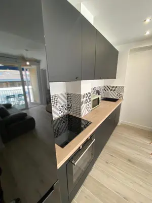 a kitchen with black and white tile on the wall at Ajaccio magnifique T2 37m2 centre ville vue mer au bord de la plage Neuf 4 couchages balcon parking privé fermé Clim wifi in Ajaccio