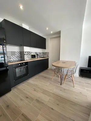 a kitchen with a wooden table and a wooden floor at Ajaccio magnifique T2 37m2 centre ville vue mer au bord de la plage Neuf 4 couchages balcon parking privé fermé Clim wifi in Ajaccio
