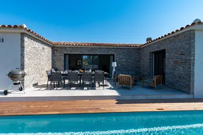 a patio with a table and chairs next to a pool at Villa Asphodede in Lecci