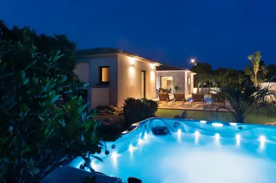 a swimming pool in front of a house at night at Villa Asphodede in Lecci