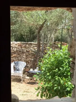 a stone wall with a chair and a table and a tree at Petite Bergerie in Bonifacio