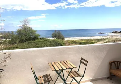 a table and chairs on a balcony overlooking the ocean at Superbe studio front de mer - Pieds dans l’eau in Linguizzetta