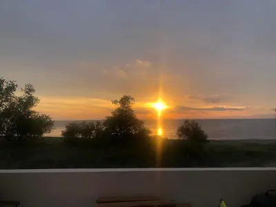 a sunset from a window with the sun in the sky at Superbe studio front de mer - Pieds dans l’eau in Linguizzetta