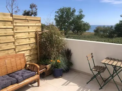 a patio with a bench and a table and a chair at Superbe studio front de mer - Pieds dans l’eau in Linguizzetta