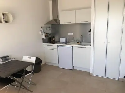 a small kitchen with white cabinets and a table at Superbe studio front de mer - Pieds dans l’eau in Linguizzetta