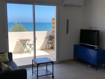 a living room with a television and a view of the beach at Superbe studio front de mer - Pieds dans l’eau in Linguizzetta