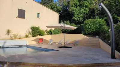 a patio with chairs and an umbrella next to a pool at Maison avec piscine entre mer et montagne in Muro