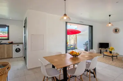 a dining room with a table and a red umbrella at Tramontana quiet place 7 min from beach swimming pool bbq in Calenzana