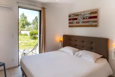 a bedroom with a white bed and a window at Tramontana quiet place 7 min from beach swimming pool bbq in Calenzana