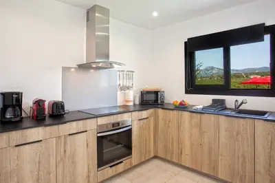 a kitchen with wooden cabinets and a window at Tramontana quiet place 7 min from beach swimming pool bbq in Calenzana