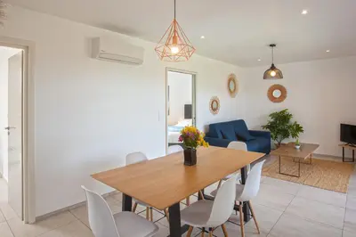 a dining room and living room with a wooden table and chairs at apart Levante shared swimming pool bbq in Calenzana