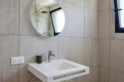 a bathroom with a white sink and a mirror at apart Levante shared swimming pool bbq in Calenzana