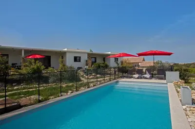 a swimming pool with red umbrellas and a house at appart Libeccio swimming pool bbq in Calenzana