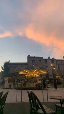 a carousel in front of a building at sunset at Superbe appartement sur le port, jacuzzi, piscine in Porto-Vecchio