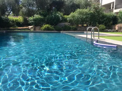 a swimming pool with blue water in a yard at Superbe appartement sur le port, jacuzzi, piscine in Porto-Vecchio