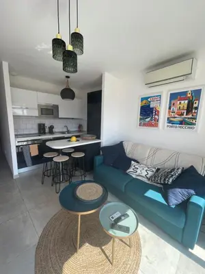 a living room with a blue couch and two tables at Superbe appartement sur le port, jacuzzi, piscine in Porto-Vecchio