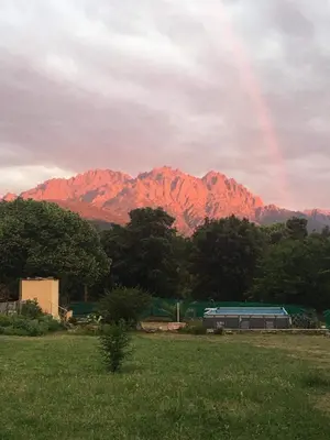 a rainbow over a mountain with a train in a field at Le coin tranquille in Morosaglia